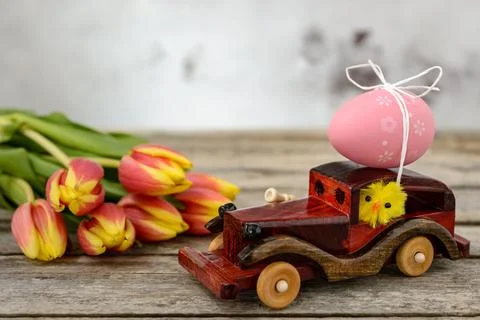 Toy car with an Easter egg and tulips Stock Photos