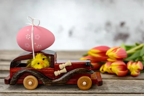 Toy car with an Easter egg and tulips Stock Photos