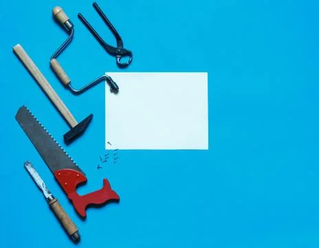 Toy carpentry tools on a blue background with a white sheet for the inscription Stock Photos