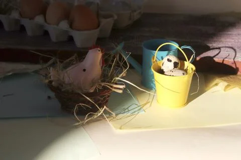 Toy chicken, eggs, hay, easter decor on a light background Stock Photos