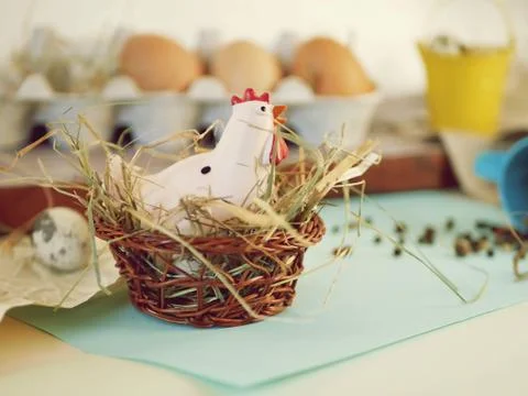 Toy chicken, eggs, hay, easter decor on a light background Stock Photos