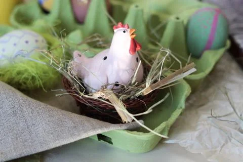 Toy chicken, eggs, hay, easter decor on a light background Stock Photos