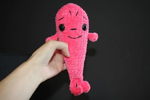 A toy on a dark black background in the hands of an unrecognizable young woman Stock Photos