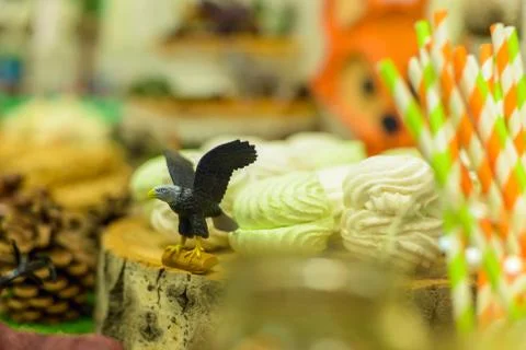 A toy eagle stands on a candy bar next to marshmallows and sweets. Close-up Fotos de archivo