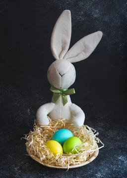 Toy easter bunny with colorful easter eggs lying in wooden plate decorated with Stock Photos
