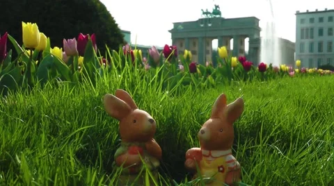 Toy easter bunny hiding in gras with tulips at brandenburg gate Stock Footage 58842069