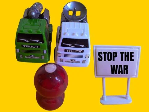 A toy figure is looking at two army trucks and the words stop the war Stock Photos