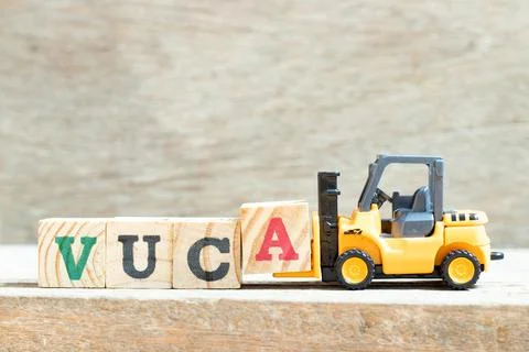 Toy forklift hold letter block a to complete word VUCA (abbreviation of Volat Stock Photos