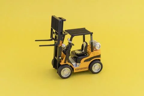 Toy forklift loader with raised up elevator on yellow background. Copy spac.. Stock Photos