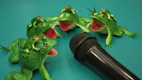 Toy frogs sing into a microphone on a green background Stock Footage 265186279