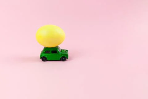 Toy green car with Easter egg on the roof. Easter card with space for text on Stock Photos