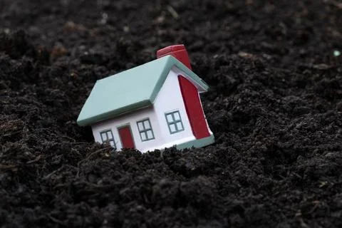 The toy house fell into the mud. Concept for real estate, mortgage, earthquak 库存照片