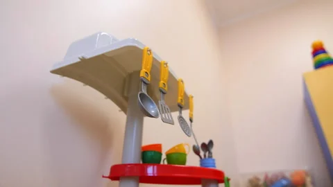 Toy kitchen with tiny utensils near white wall in playroom Video stock 170312160