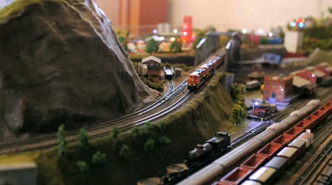 Toy model train curves around mountain passing a classic American town Stock Footage 52551396