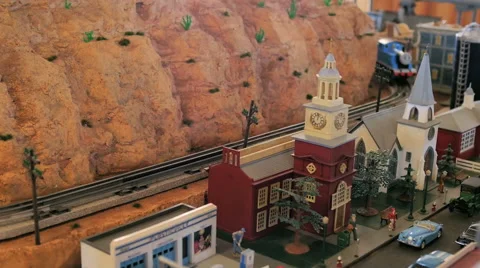 Toy model train passes town with hall, church, and cars in a railroad set Stock Footage 52551263