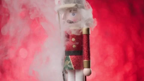 The Toy Nutcracker covered in thick fog, twirls lively in front of a bright red Vídeos de archivo 321679336
