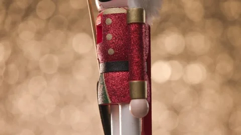 Toy Nutcracker spins gracefully against a vibrant golden bokeh background, Stock Footage 321680813