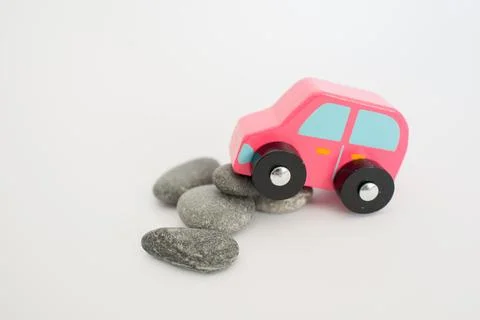 Toy pink car having problems with stones on the road with white background Photos