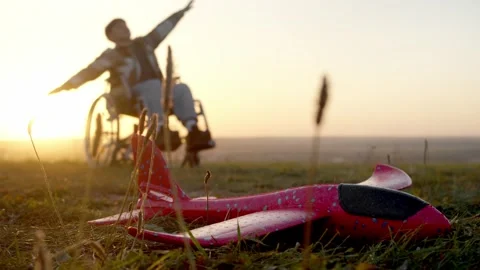 Toy plane dominates foreground in evening light as child with limited mobility Stock Footage 318004937