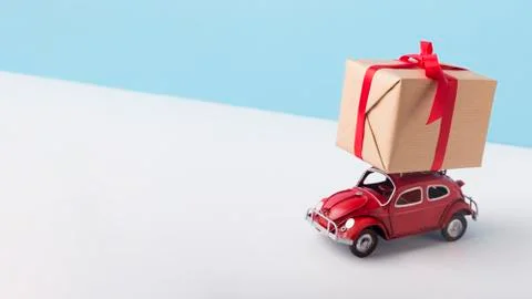 Toy red car Volkswagen Beetle delivering Christmas presents over creative winter Stock Photos