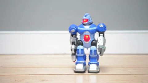 Toy robot walks then falls over onto wooden floor Stock Footage