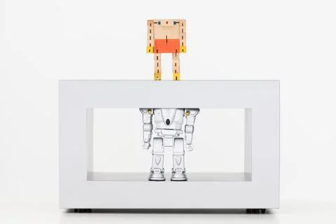 Toy robots standing on coffee table, the one above looking down at the one below Fotos Stock