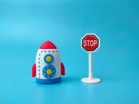 A toy rocket positioned next to a miniature octagonal red stop sign on a bl.. Stock Photos