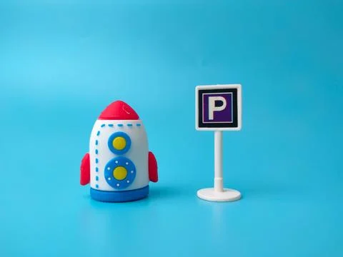 A toy rocket positioned next to a miniature parking sign with the letter P .. Stock Photos