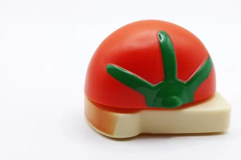 Toy slice of bread with half tomato on white background Stock Photos