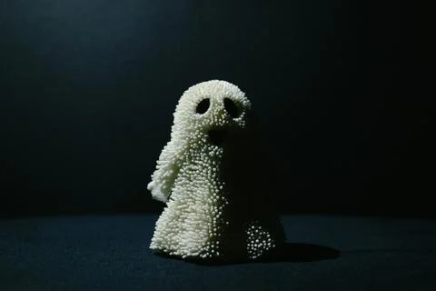 Toy smiling ghost standing in semi-darkness and illuminated by light Stock Photos