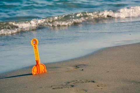 Toy Spade at the Beach With Waves in the Background Stock Photos