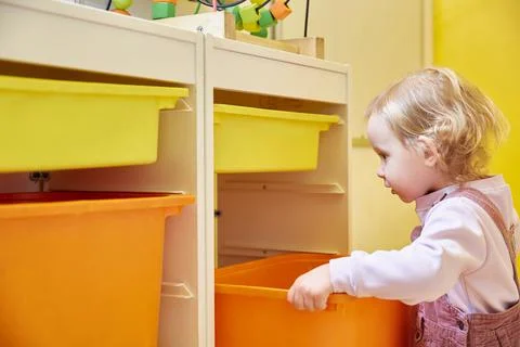 Toy storage system. The child puts the color box in the rack Stock Photos