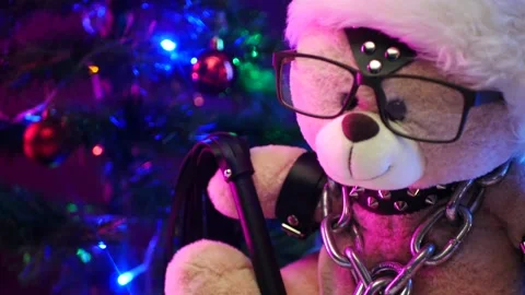 A toy Teddy bear dressed in leather belts and a Santa Claus hat in the New year Stock Footage 143557538