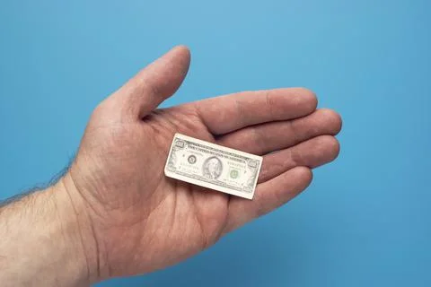 Toy tiny hundred dollar bill in open palm of a man, financial concept Фото