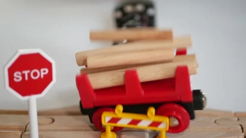 Toy train with flashing red light crashes into a toy rail carriage full of logs. Stock-Footage 139837805