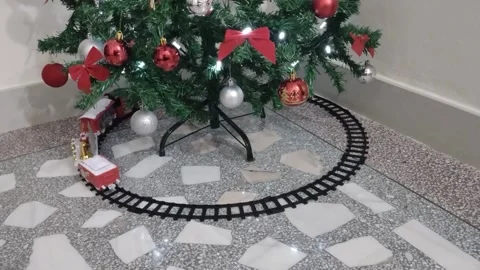Toy train running on rails under a Christmas tree Stock Footage 225085586