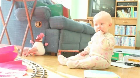 Toy train runs past one year old girl Video stock 12760615