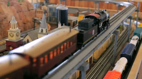 Toy trains passing through model of classic american town on a railroad set Stock Footage 52550642