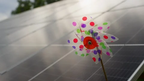 A toy windmill spins against a background of solar panels. Stock Footage 314461969