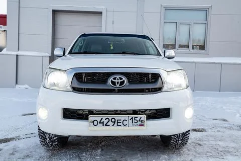 Toyota hilux pickup in white color on the snow near grey wall front view of.. Stock Photos