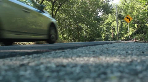 Toyota prius drives down wooded road low angle Stock Footage