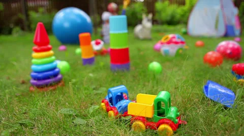 Toys on grass and unrecognizable baby on background (dolly shot) Stock Footage