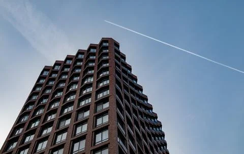A trace of a passing plane over a modern multi-storey business class building Foto stock