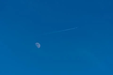 Trace of the plane on the background of the moon. Stock Photos
