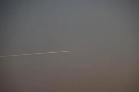 Trace of plane on a gradient sky from blue to orange. Stock Photos
