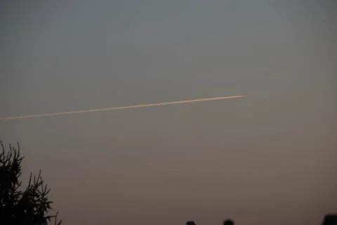 Trace of plane on sky during sunset Stock Photos
