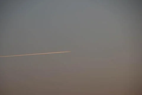 The trace of plane on the sky on the fire sunset Stock Photos