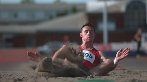 Track athlete landing in sand on long jump in super slow motion, shot on Phantom Stock Footage
