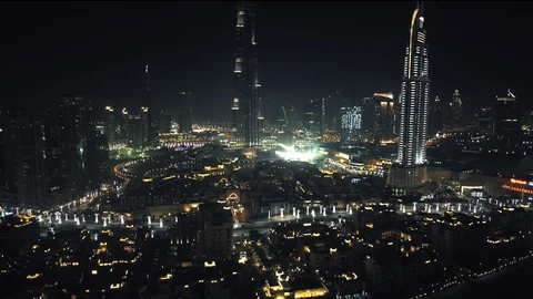 Track back at 100m over Downtown Dubai while panning up to reveal Burj Khalifa Stock Footage 98984192
