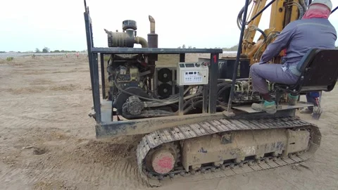 Track-mounted mini drilling rig operating on a sandy construction site with Stock Footage 343010277